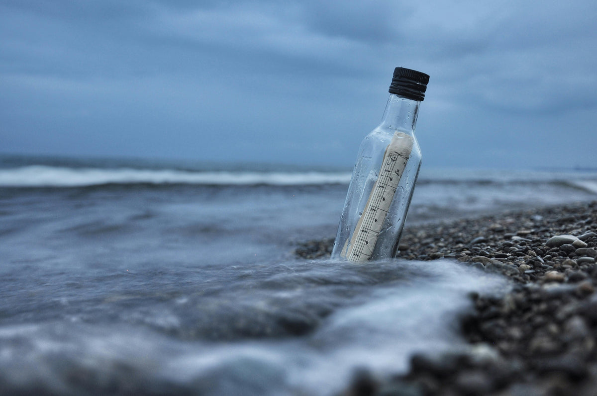 Flessenpost met opgerolde boodschap aangespoeld op een kiezelstrand